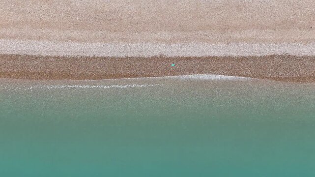Birds Eye View Drone shot of English Coastline on a calm cloudy day, with stone beach and soft waves