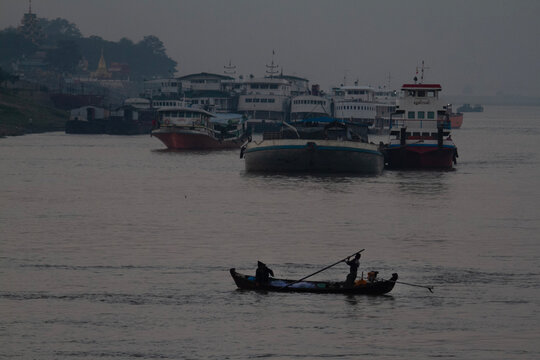 A small boat goes across Irrawaddy river on a misty dawn.