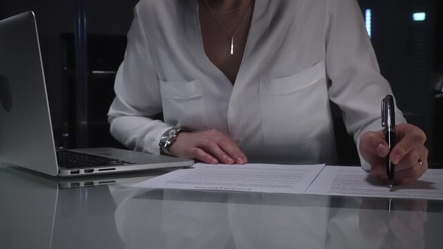 Businesswoman lawyer looking through a contract document before signing, while working in a corporate office at night. Audit, business and overworking concepts