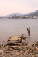 Fototapeta premium Abandoned pier and Panoramic view of Bodrum city, Turkey and Saint Peter Castle and marina. Summer landscape, popular travel destination. Selective Focus. Long Exposure shoot. tranquility scene. 