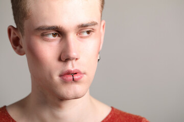 Naklejka premium Young man with piercings on light grey background, closeup. Space for text