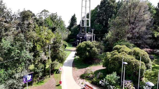 Cinematic aerial raising toward the monumental cross on Monte Philippi and panning down to reveal the lush native forest and the vast blue waters of Lake Llanquihue in Puerto Varas, Chile