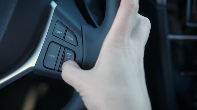 Woman speeds on the steering wheel of a car. View of a woman's finger pressing a wheel button in a modern car