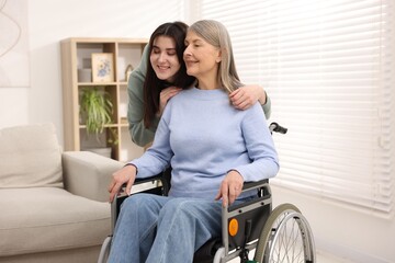 Senior woman in wheelchair with her caretaker at home