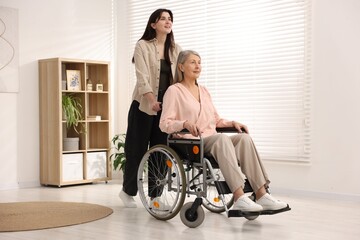 Senior woman in wheelchair with her caretaker at home