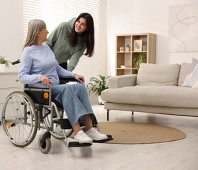 Senior woman in wheelchair with her caretaker at home