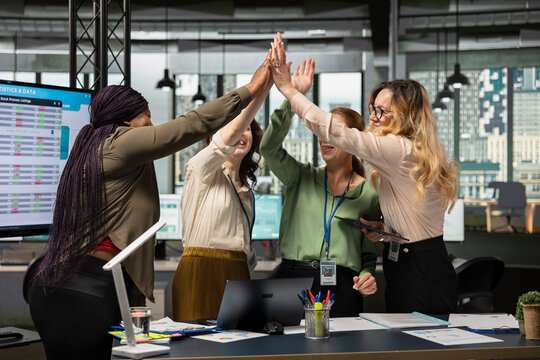 Multiethnic colleagues sharing a high five and celebrating their team success, feeling pleased with their victory and achievement in developing the company activity. Office accomplishment.