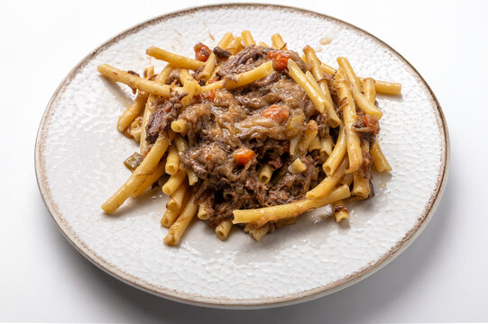 Ziti alla genovese, traditional Neapolitan pasta with slow cooked beef and onion rag&ugrave;, served on white plate