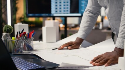 African american contractor examining architectural blueprints plans on table, review zoning regulations for construction project approval. Site preparation master plan and infrastructure. © DC Studio