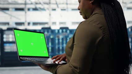 Computer scientist at work using green screen laptop in data center to check hardware for system stability. Manager using mockup notebook to oversee server farm gear, camera B