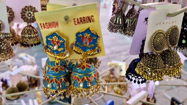 Vibrant blue and gold jhumka earrings hang on display at a Jaipur market. These intricate accessories reflect the traditional Rajasthani craftsmanship found near the Hawa Mahal.