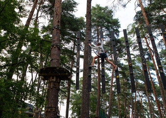 Fototapeta premium Boy Walking a Rope Adventure Course in a Pine Forest on a Summer Day.