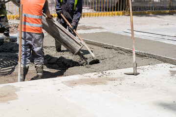 Construction workers pouring wet cement onto a busy city street during daytime