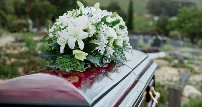 Flowers, casket and funeral at graveyard for burial service, ritual or memorial outdoor for loss. Grief, mourning and coffin with bouquet of floral plants for respect at cemetery for remembrance
