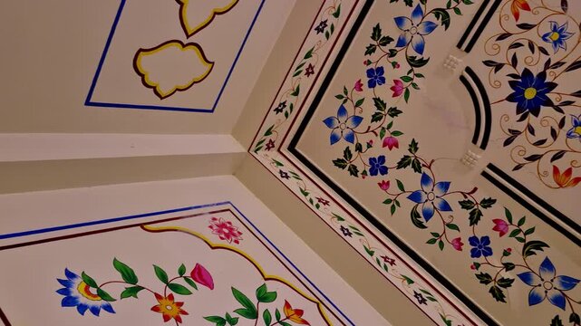 Hand-painted floral patterns and scalloped borders decorate a Jaipur ceiling. The intricate blue and pink blooms showcase the refined artistic tradition of Rajasthani home interiors.