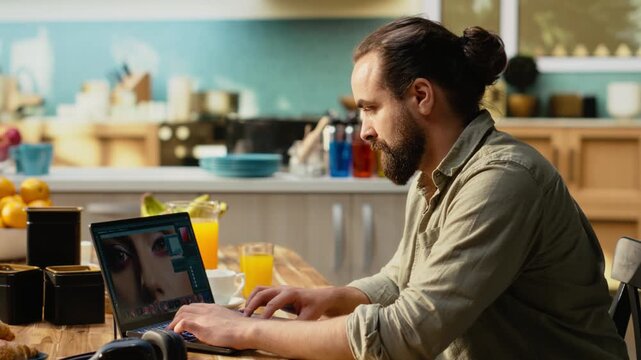 Professional photo editor developing raw images on laptop in kitchen workspace, creative process with retouching and color grading, working from home indoors. Photography industry workflow.