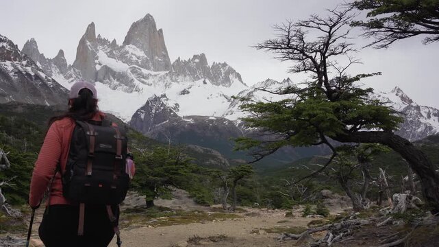Woman hiking toward the snowy granite peaks of Mount Fitz Roy in nature