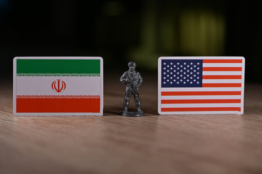 A tin soldier on the background of the flags of the United States and Iran.