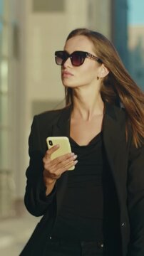 Modern woman in business casual outfit confidently walking through urban environment during daylight