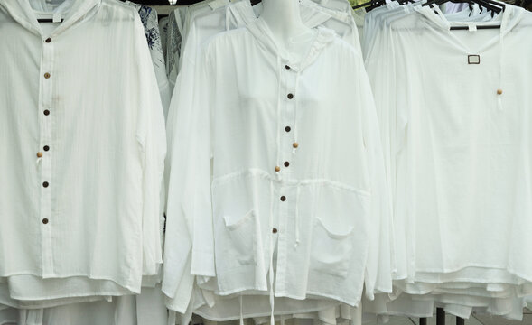 White Cotton Shirts Hanging on Rack in Market Stall
