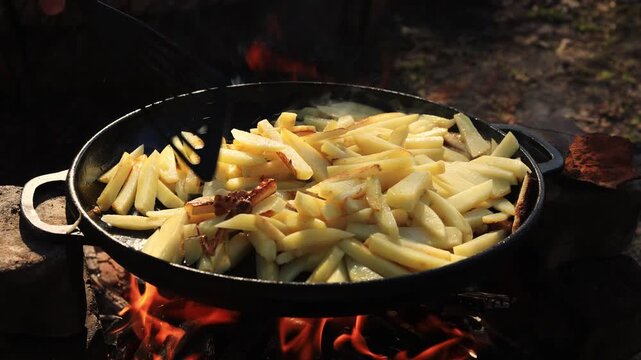 Cooking french fries in a cast iron pan over an open campfire