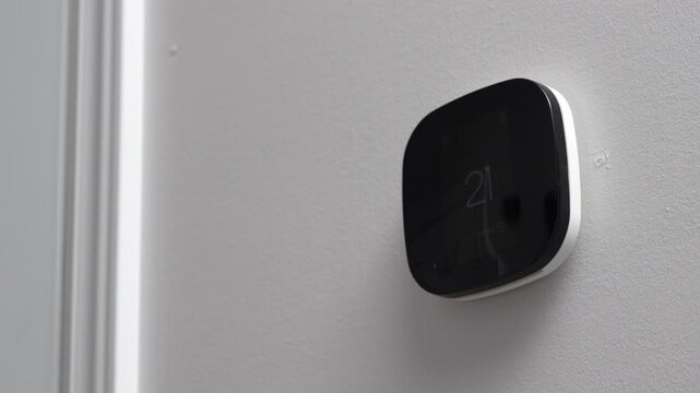 Smart thermostat displays temperature settings on a wall in a modern interior, showcasing sleek design and functionality in a residential environment
