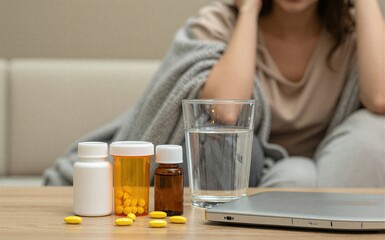 Woman sits home pills and water nearby suggesting illness or