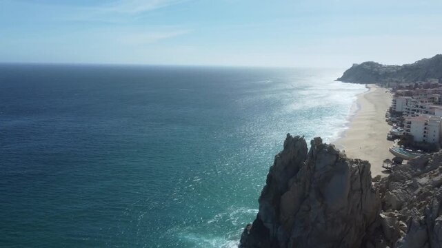 Aerial top-down view of turquoise sea waves crashing on granite rocks near Cabo San Lucas coastline, Mexico