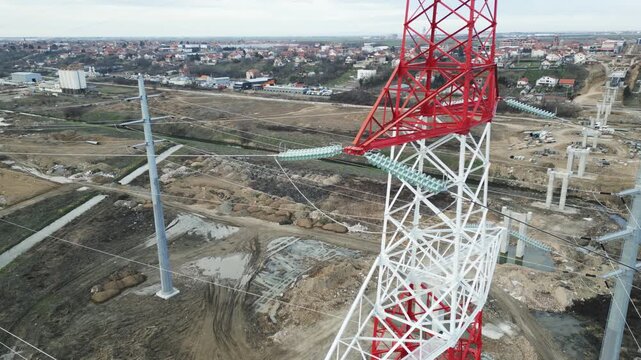Power transmission tower steel construction detail seen from drone close-up, high-voltage electricity cables and insulators