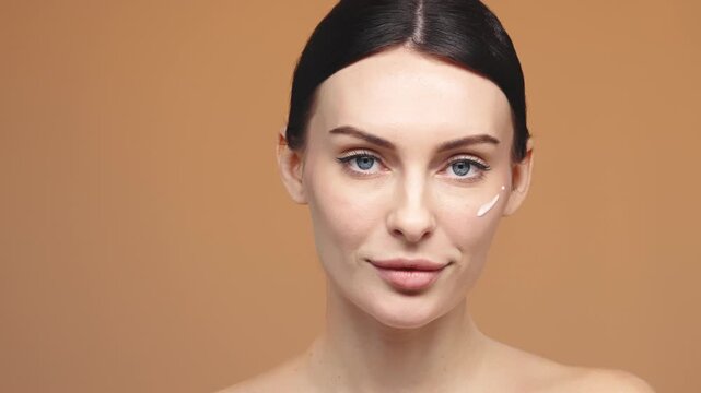 Young woman applying hydrating serum on face isolated on background. Skincare and hydration concept.
