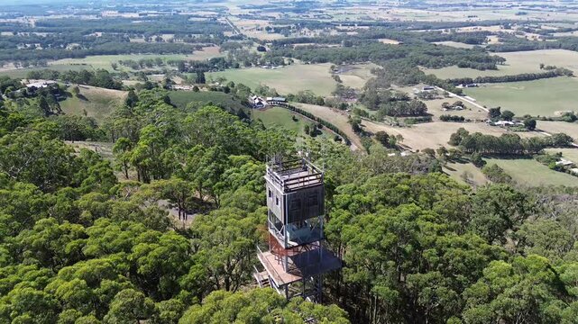 Aerial view of fire lookout tower above forest with rural landscape background