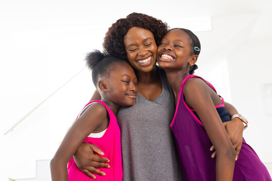 Family mother and two girls greeting, hugging cheeks together at home, showing affection in tanks