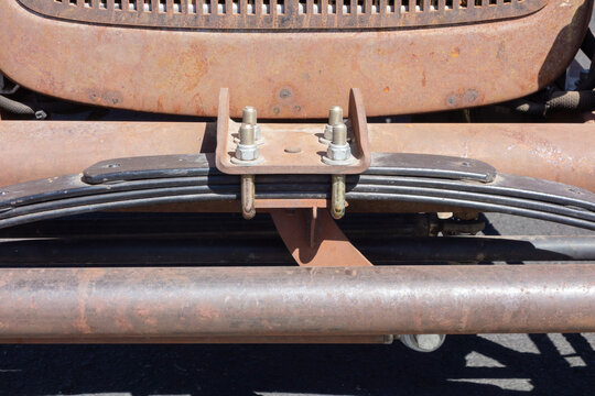 Clamped multi-leaf spring suspension assembly of a vintage car attached to an axle