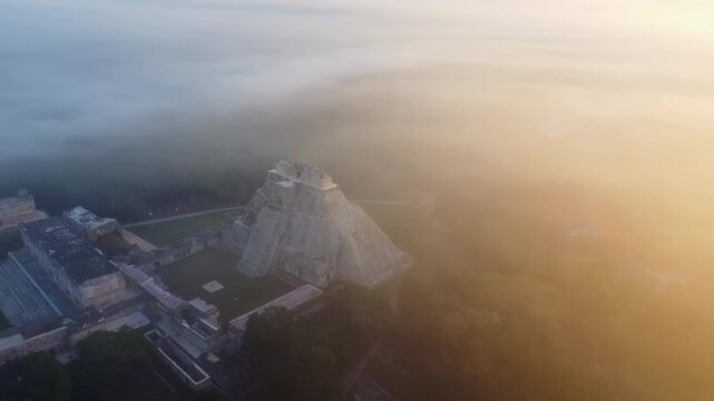 Aerial drone view of the Temple of the Inscriptions at Palenque archaeological site emerging through morning mist in the Chiapas jungle, Mexico, showing ancient Mayan ruins surrounded by dense rainfor