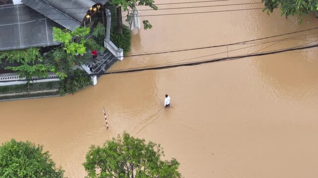 In Hanoi, Vietnam, a man wades through floodwaters after heavy rainfall. Flooding is a growing concern due to climate change and urbanization in the city.