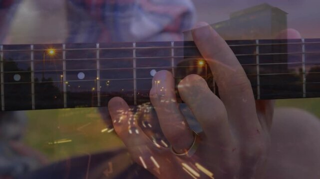 Musician's left hand fretting chords causing highway lights overlay guitar neck showing music