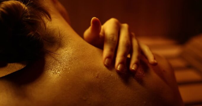 Woman sweating and touching her skin in sauna. closeup. Camera moving forward