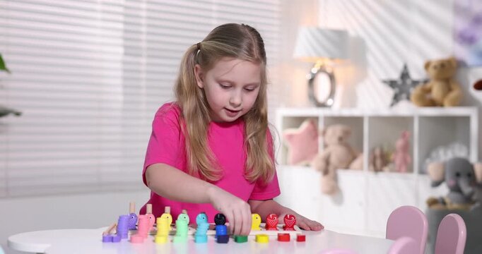 Little girl playing with educational toy at table indoors
