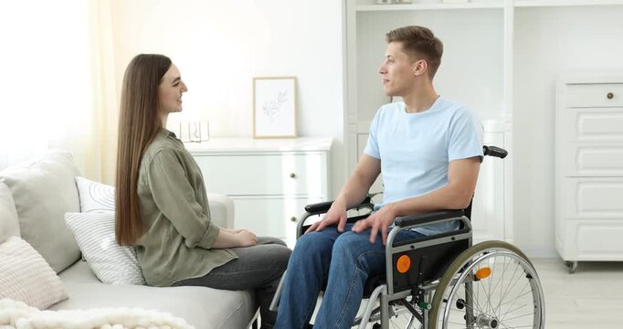 Man in wheelchair talking with woman at home