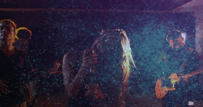 Lead female singer gripping wired mic, headbanging after drummer cue, causing music rim light haze
