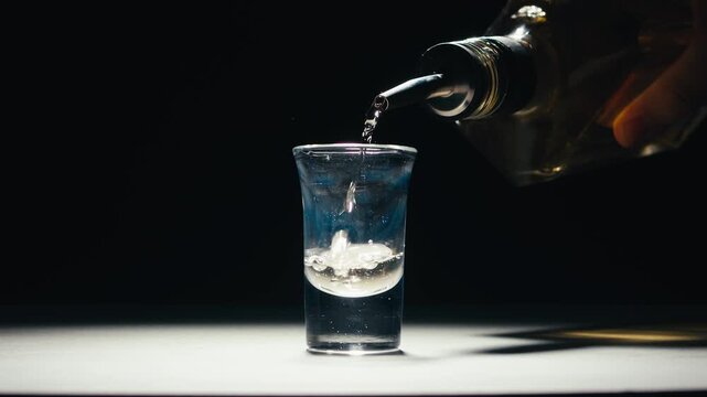 Mexican Tequila Mezcal pouring with lime and salt on a stone table. Strong vodka rum alcoholic drink is poured from a bottle into a shots.