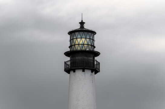 Historic Lighthouse Tower with Glowing Beacon Against Dramatic Cloudy Sky