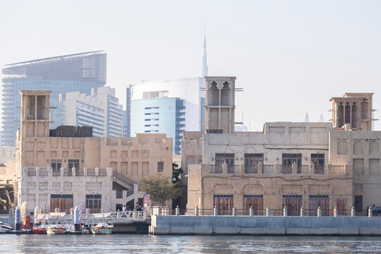 12.12. 2025, Dubai, UAE. Traditional dhow boats and abras on Dubai Creek with Deira old district heritage buildings and modern skyscrapers in the background. Contrast of old and new Dubai, UAE.