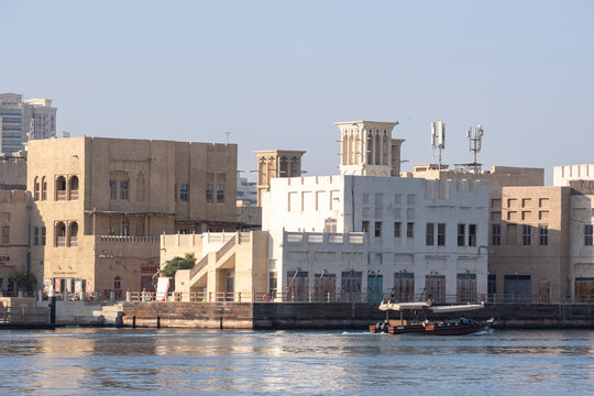 12.12. 2025, Dubai, UAE. Traditional dhow boats and abras on Dubai Creek with Deira old district heritage buildings and modern skyscrapers in the background. Contrast of old and new Dubai, UAE.