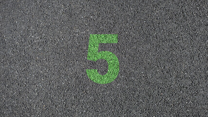green number five painted on dark asphalt road surface green number four painted on dark asphalt road surface