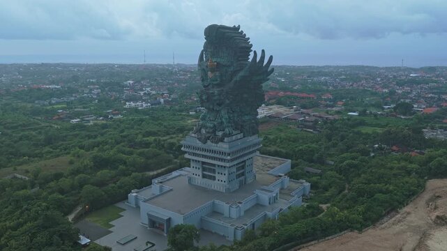 Aerial view of the massive garuda wisnu kencana statue, a hindu cultural landmark overlooking the lush landscape and city of bali