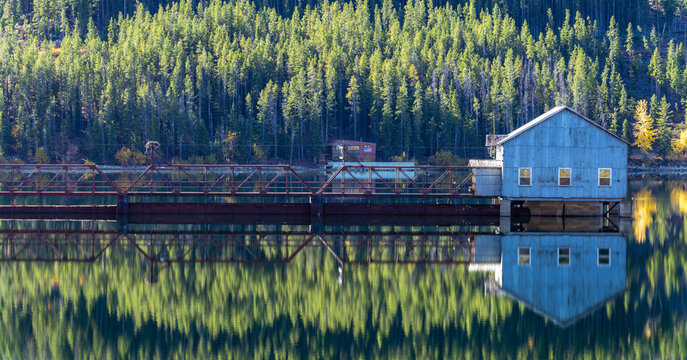 Calm Lake Reflection with Rustic Bridge and Boathouse in Forest, Montana
