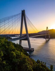 Obraz premium A majestic cable-stayed bridge spans a serene body of water at sunset