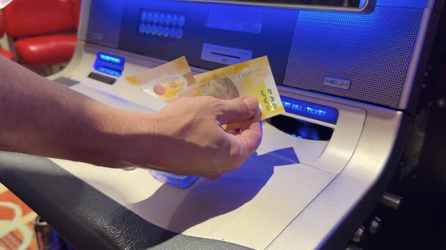 Close Up of Person Inserting Cash Into Slot Machine in Manila
