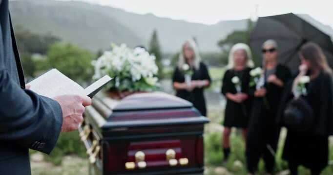 Funeral, hands or priest with bible at graveyard, memorial service or scripture for religious practice. Reading, Christianity or people with pastor for farewell ceremony, casket or burial prayer